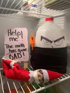 an elf is sitting on top of a refrigerator shelf next to a sign that says help me the milk has gone bad