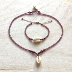 Jewelry made of natural cowrie shells (16 - 19 mm), lavender / purple color original Czech glass beads (3.1 / 4.1 / 5.6 mm Rocailles Preciosa) and waxed polyester cord (original Linhasita 1 mm). A necklace is available in 3 lengths (40 cm = 15.74 inches, 45 cm = 17.71 inches or 50 cm = 19.68 inches). The length of a bracelet is adjustable and should fit all wrists sizes.     The jewelry is robust and fully waterproof. If you have any questions/wishes, please don't hesitate to contact me! Handmade Purple Necklaces For Beach, Handmade Purple Beach Necklaces, Bohemian Adjustable Pink Shell Necklace, Adjustable Lavender Bracelets For Beach, Bohemian Pink Shell As Gift, Bohemian Pink Shell As A Gift, Bohemian Pink Shell Gift, Purple Beaded Bracelets For The Beach, Purple Beaded Bracelets For Beach