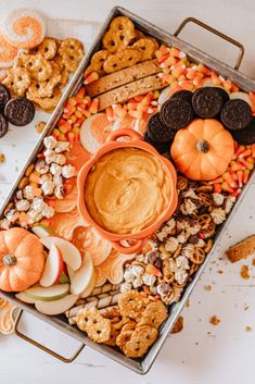 a tray filled with cookies, crackers, candy and pumpkins next to other snacks