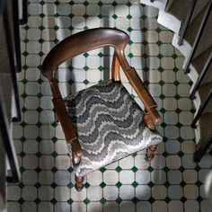 a wooden chair sitting on top of a tiled floor next to a stair case and handrail