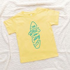 Looking for a cute tee for your kids? We have the perfect The Waves Are Calling Surf Board graphic tee addition to their closet! Also available in youth tees. Cotton T-shirt With Cartoon Print For Playwear, Trendy Cotton T-shirt For Playwear, Family Matching Summer T-shirt With Screen Print, Yellow Cartoon Print T-shirt For Summer, Casual T-shirt With Letter Print For Play, Casual Letter Print T-shirt For Play, Summer Cartoon Print Playwear T-shirt, Fun Graphic Print T-shirt For Playwear, Family Matching Cartoon Print T-shirt For Summer