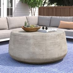 an outdoor living area with couches, table and potted plant on the rug