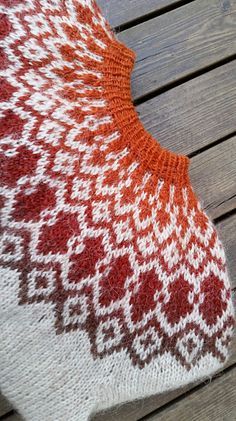 an orange and white knitted cushion sitting on top of a wooden floor