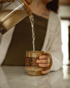 a person pouring water into a coffee cup