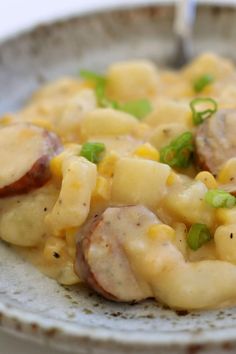 a white plate topped with macaroni and cheese covered in meat, peas and sauce