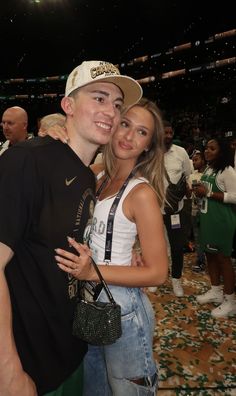 a man and woman posing for a photo in front of a crowd at a sporting event