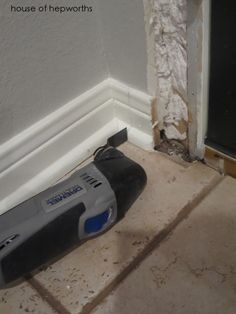 a cordless drill is laying on the floor in front of a wall that has been torn down