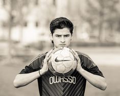 a man holding a soccer ball in front of his face while wearing a nike shirt