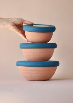 three bowls stacked on top of each other in front of a person's hand