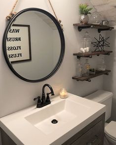 a bathroom sink sitting under a mirror next to a shelf filled with bottles and candles