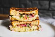 two grilled cheese sandwiches stacked on top of each other with red onions and lettuce