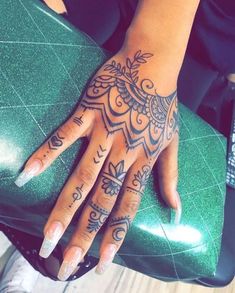 a woman's hand with tattoos on it sitting on a green chair in front of a window