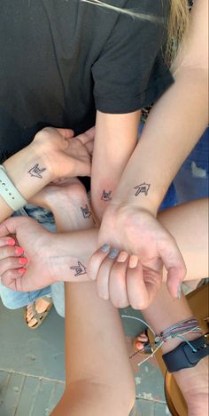 several people holding their hands together with tattoos on them