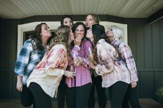 a group of women standing next to each other in front of a house with their mouths open