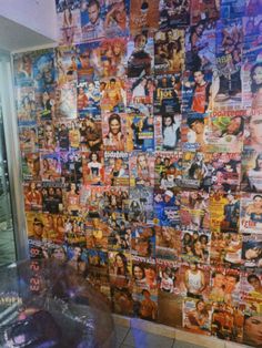 a wall covered in posters and pictures next to a window