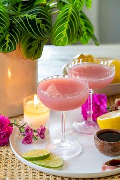 two cocktails on a tray with flowers and candles