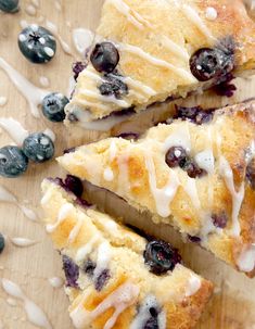 blueberry scones with icing on a cutting board next to some blueberries