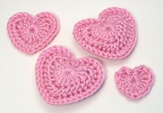 three crocheted pink hearts on a white surface