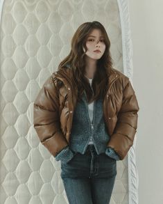 a woman standing in front of a mattress with her hands on her hips and arms behind her back