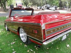 an old red car is parked in the grass