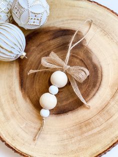 three ornaments are sitting in a bowl on a wood slice, tied with twine