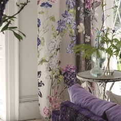 a living room filled with furniture and flowers on the wall next to a glass table