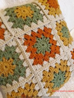 a crocheted granny blanket with orange, green and yellow flowers