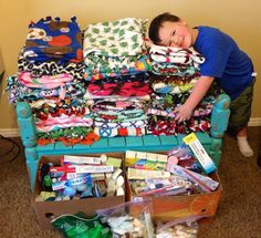 a young boy laying on top of a bed covered in lots of clothing and toys