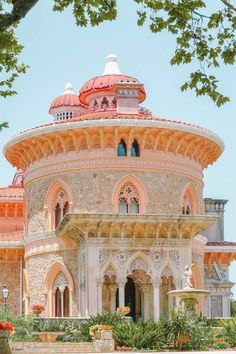 an ornate building with red and white domes on it's roof, surrounded by greenery