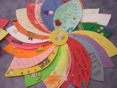 a bunch of colorful paper fan shaped like a flower with writing on it's side