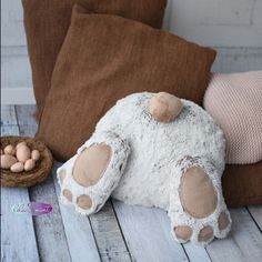 a stuffed animal laying on top of a wooden floor next to some pillows and eggs