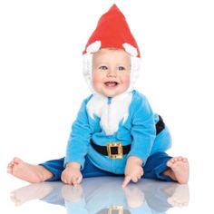 a baby wearing a santa hat and sitting on the floor with his legs spread out