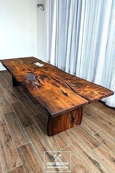 a wooden table sitting on top of a hard wood floor next to a curtained window