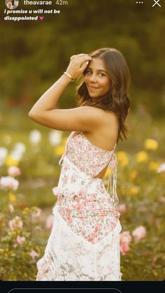 a beautiful young woman in a floral dress posing for the camera with her hand on her head