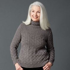 an older woman with white hair wearing a gray sweater