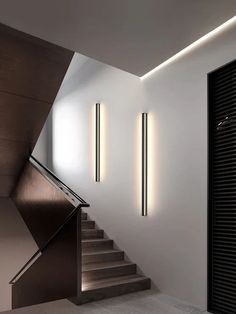 some lights that are on the side of a stair case in a room with white walls