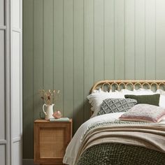 a bedroom with green walls and white bedding, along with a wicker headboard