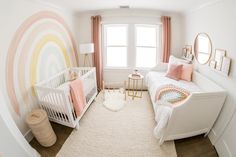 a baby's room with a white crib, pink and yellow decor, and a rainbow wall mural