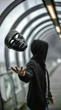 a person in a black hoodie with a mask on their face and hands out