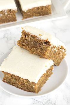 two pieces of carrot cake on a white plate with one slice cut out and the other half eaten