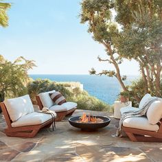 an outdoor fire pit surrounded by chairs and trees with the ocean in the background on instagram