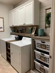 a washer and dryer in a room with white cabinets, drawers and baskets