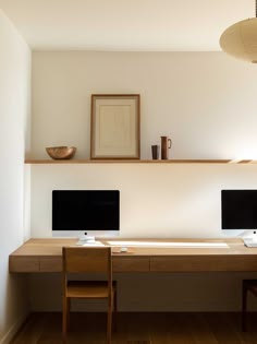 two computer monitors sitting on top of a wooden desk