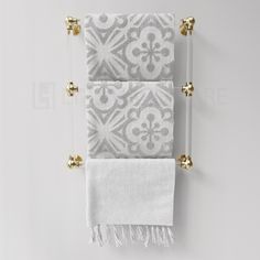 two white towels hanging on the wall with gold handles and tassels in front of them