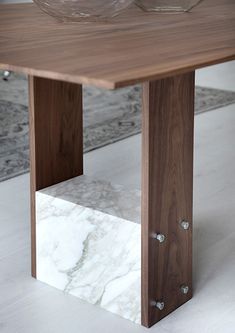 a wooden table sitting on top of a white floor next to a rug and window