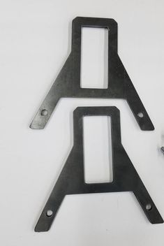 two pieces of metal sitting next to each other on a white surface with screws