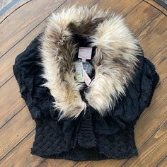 a jacket with fur collar on top of a wooden floor