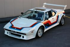 a white car with red, blue and orange stripes parked in a parking lot next to a building