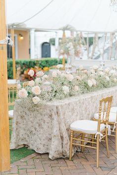 the table is set up with white flowers and greenery for an outdoor wedding reception