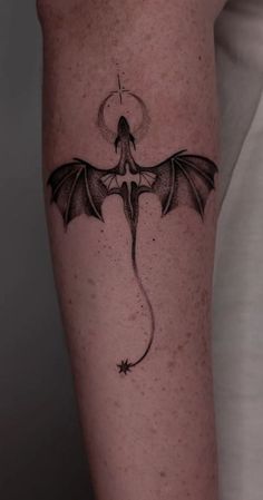 a black and white photo of a dragon tattoo on the right arm with an arrow